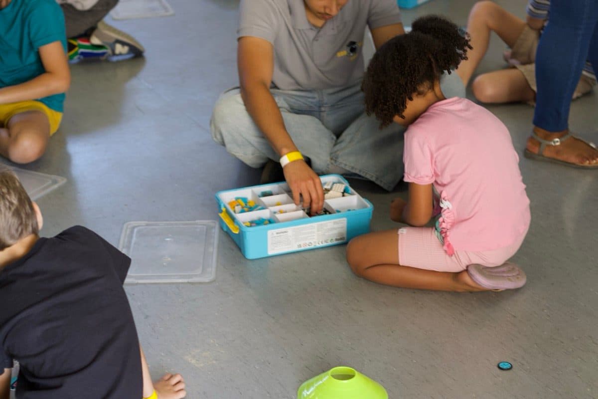 A facilitator helping a child with a robotics kit in the classroom