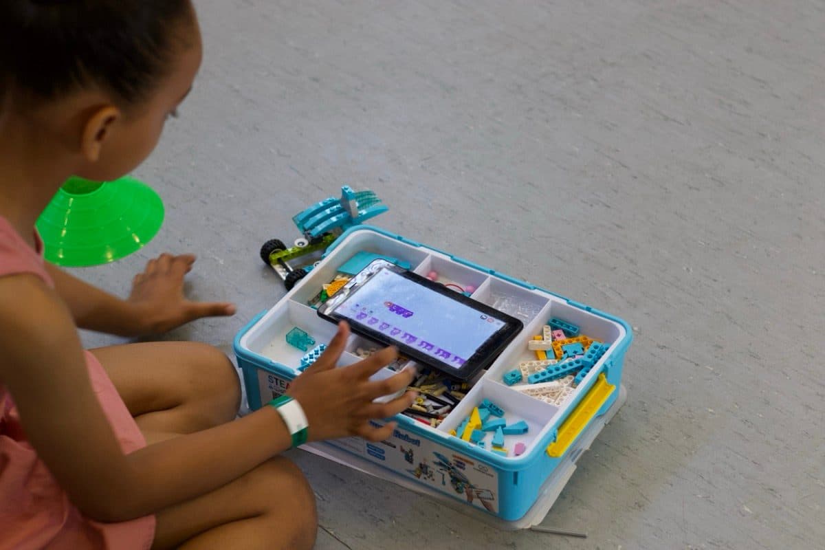 Girl using a tablet to code alongside her robotics kit