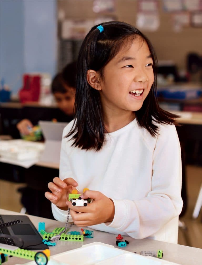 Girl smiling while holding a robot she built in class