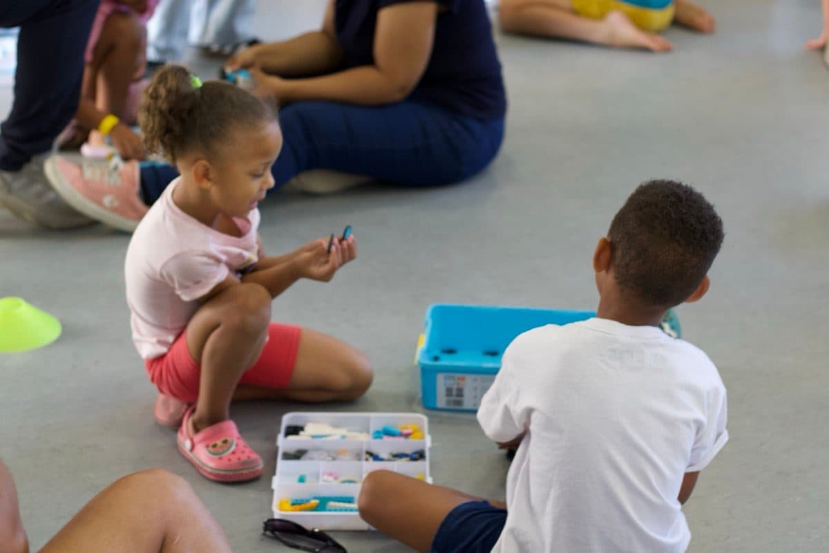 Young children exploring a robotics kit on the floor
