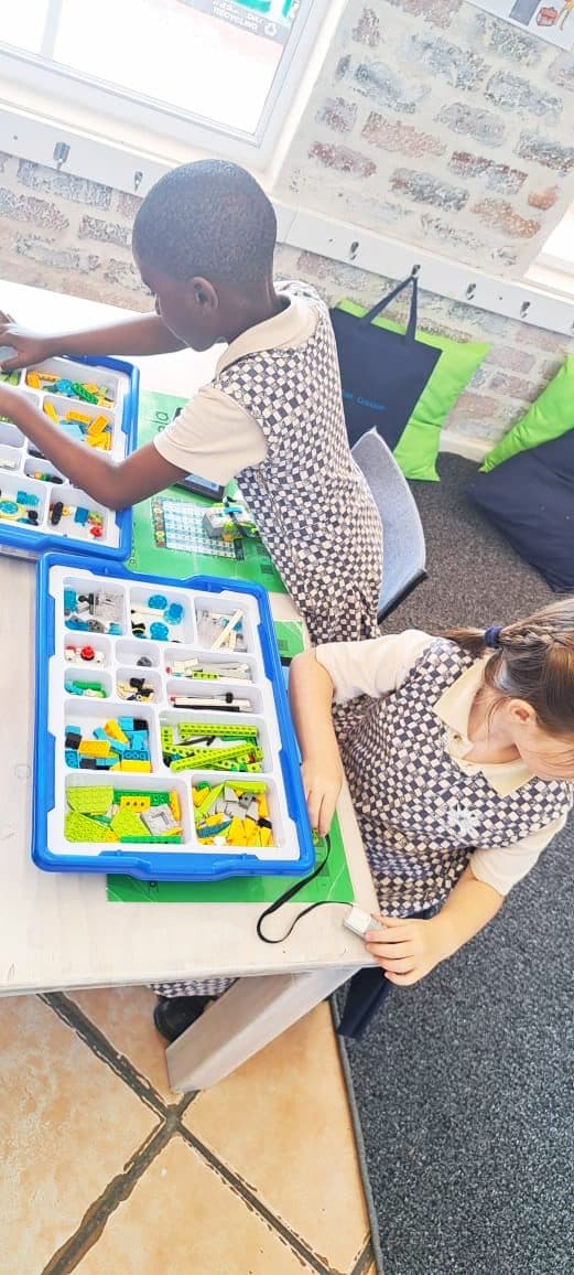 Two children in school uniform working with robotics kits