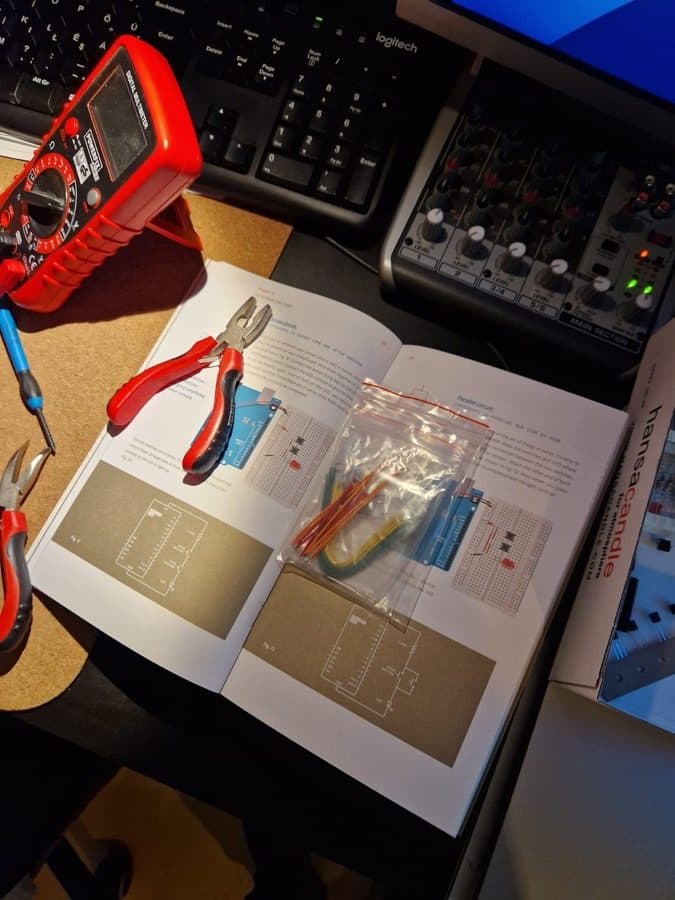 Arduino project workbook open with components in front of a laptop