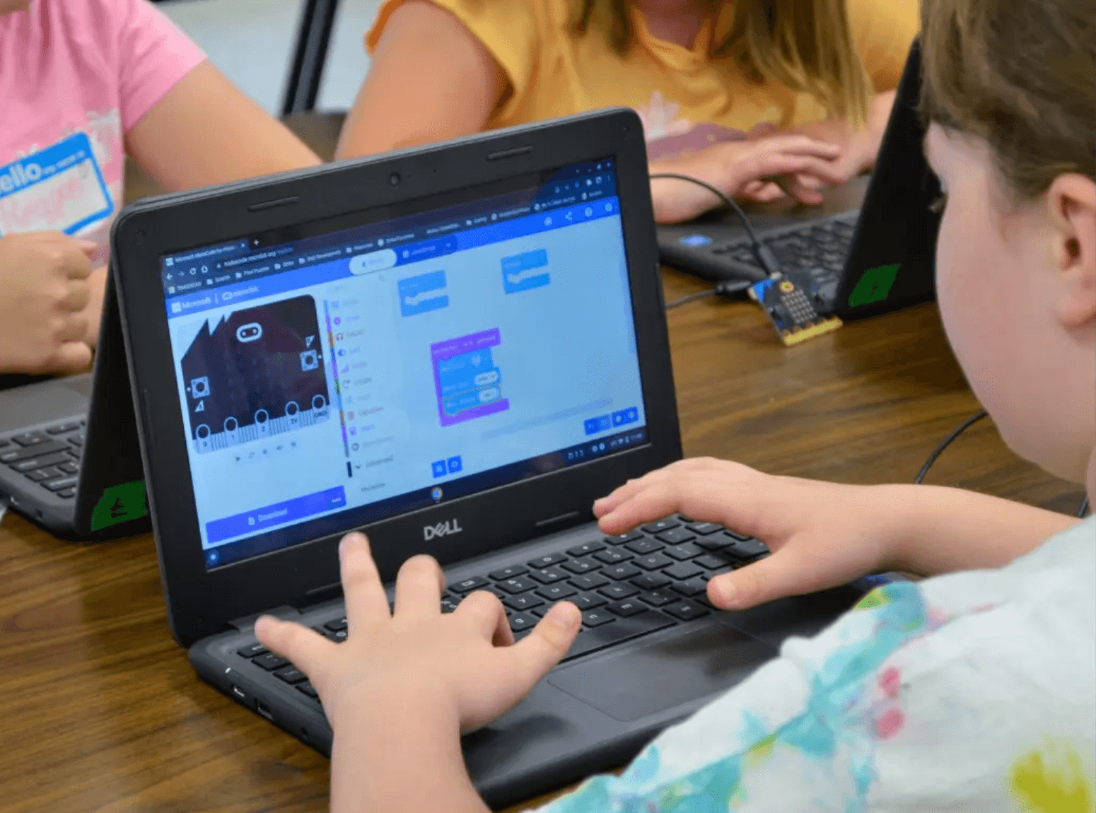 Young girl coding with MakeCode blocks on a laptop