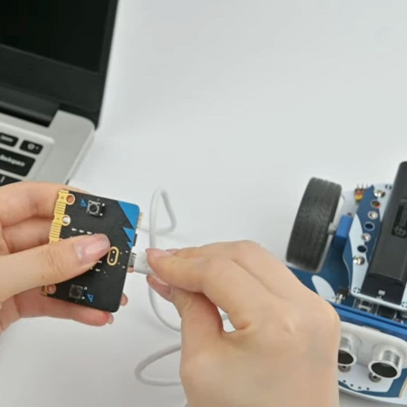 Hand plugging a BBC micro:bit into the Cutebot Pro robot car