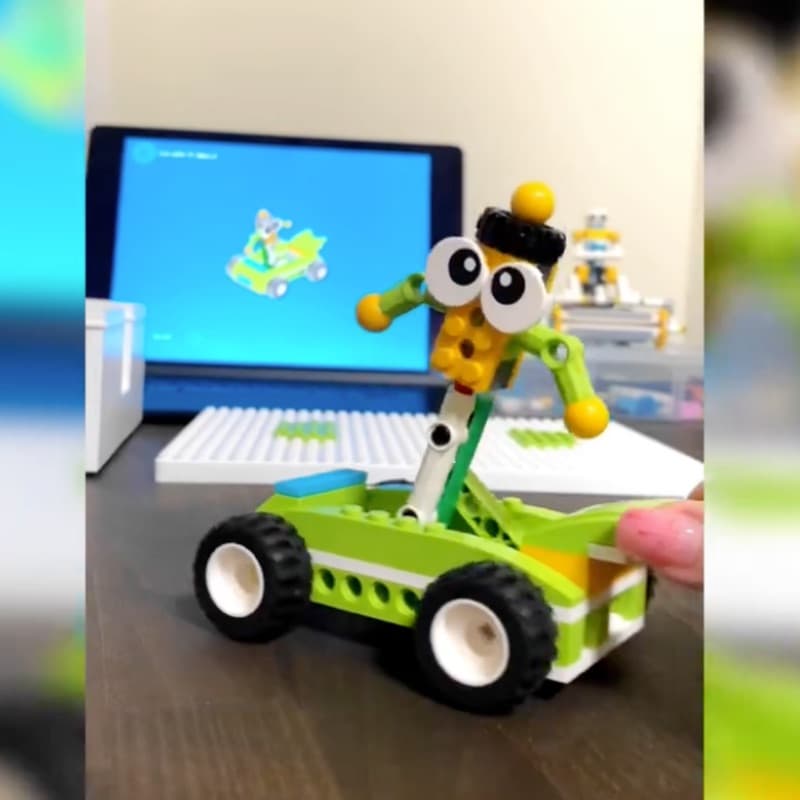 Robot man figure in a car build next to a tablet showing the Makerzoid app