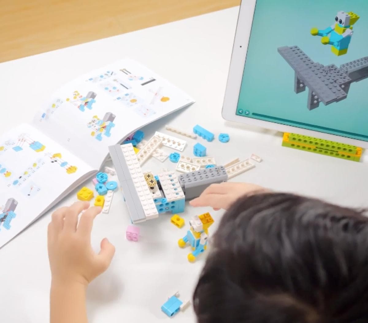 Child building a robot while coding on tablet