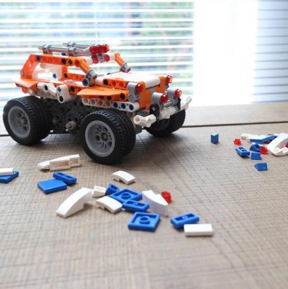 Makerzoid Superbot orange racing car model built with spare bricks scattered around it
