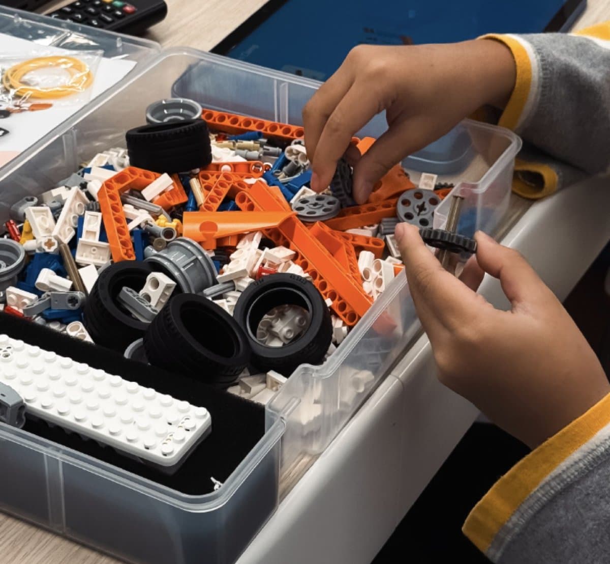Child's hands reaching into the Makerzoid Superbot storage box to pick out building pieces