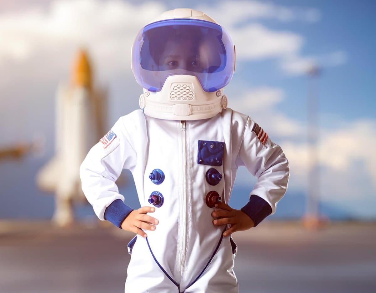 Boy wearing the NASA astronaut helmet with a space scene in the background