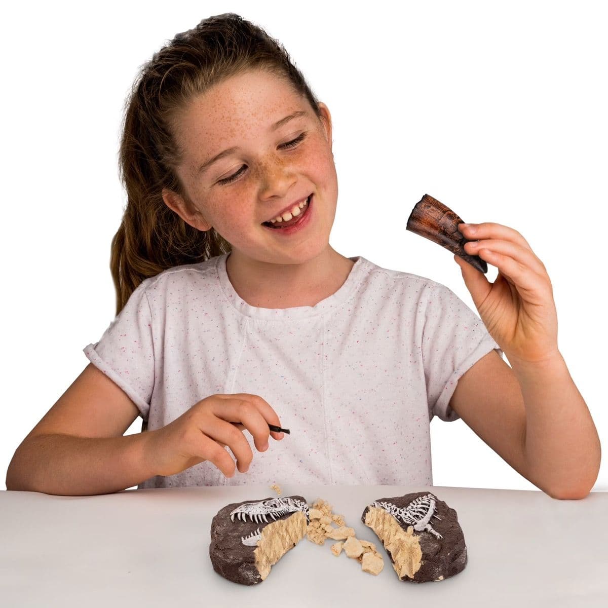Girl carefully excavating a fossil from a dig brick