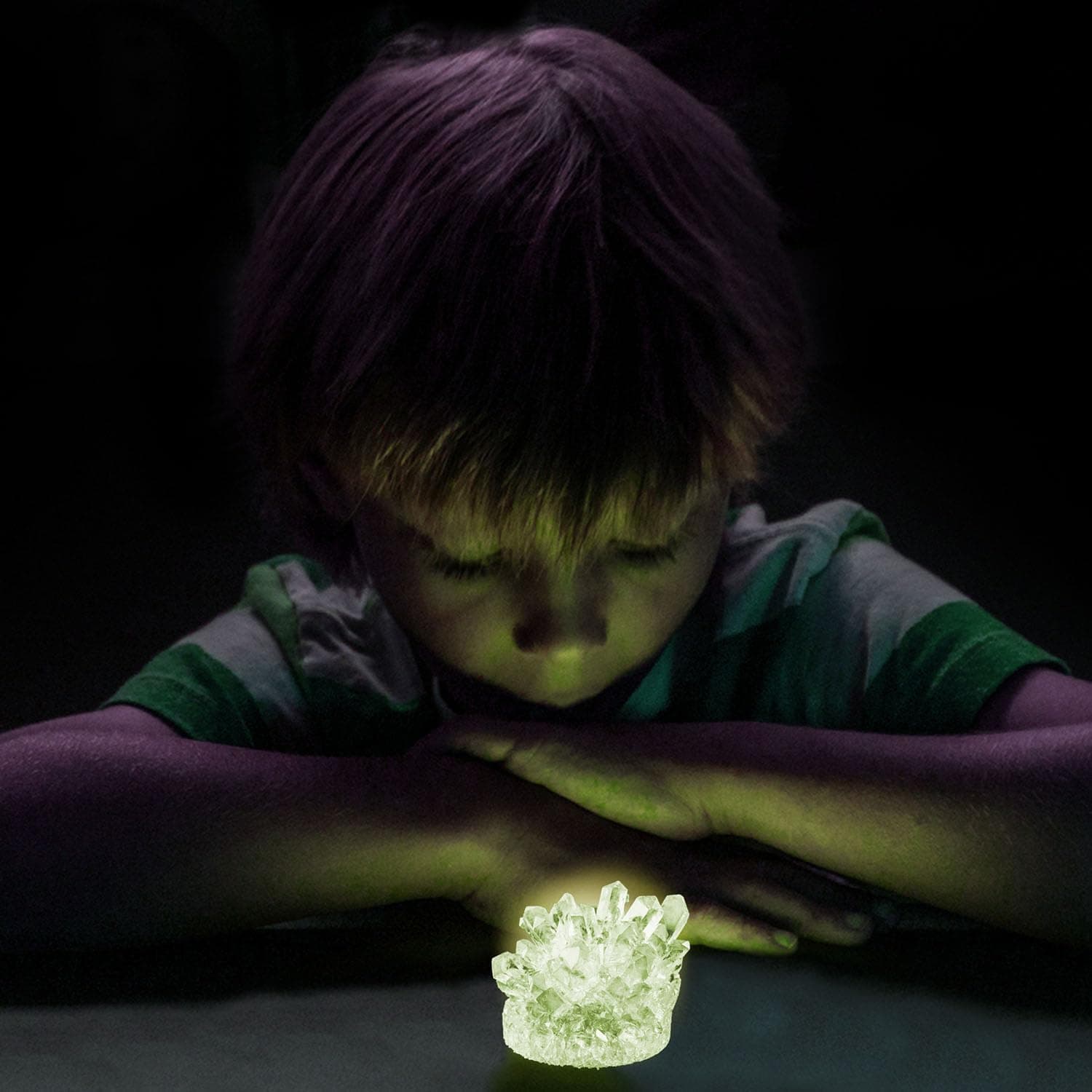 Boy looking at a glowing crystal in the dark