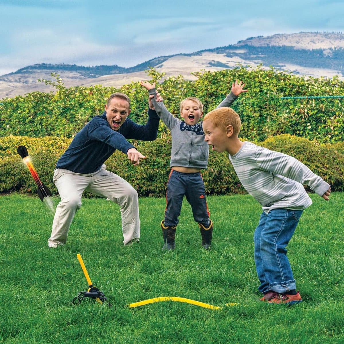 A dad and children playing excitedly with the National Geographic Light-Up Air Rockets