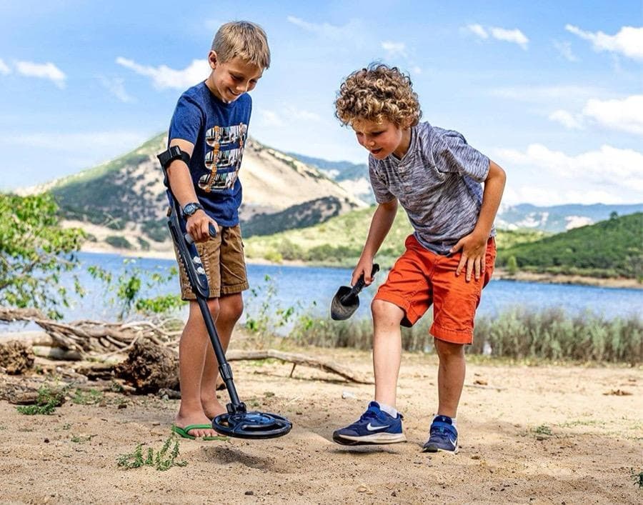 Children using a National Geographic metal detector to search for buried treasure outdoors