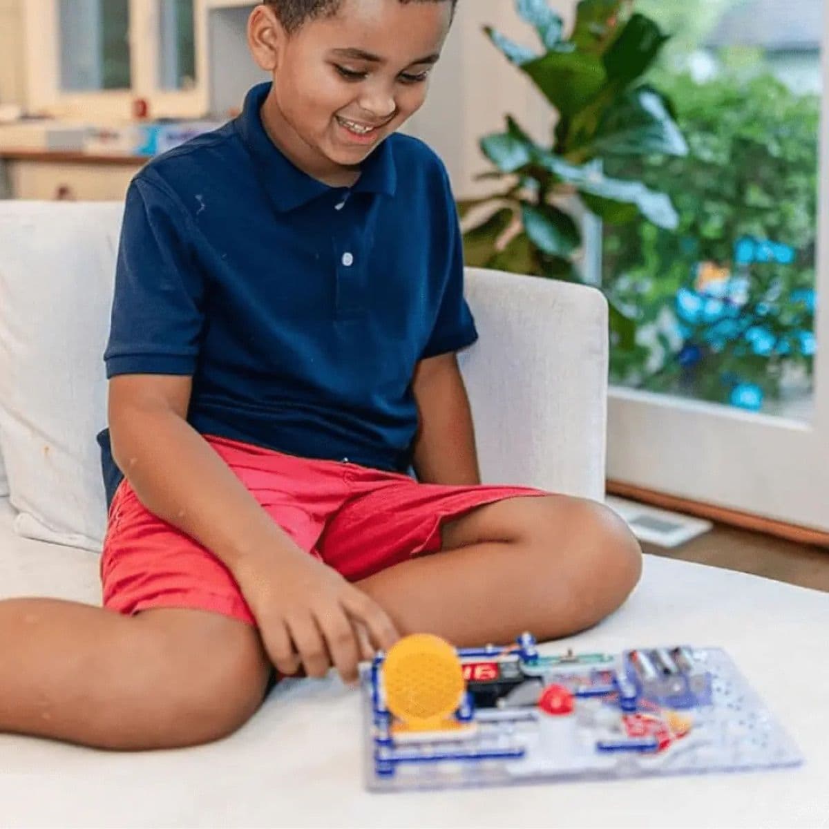 Boy engaged with the Snap Circuits Arcade, assembling components on the grid