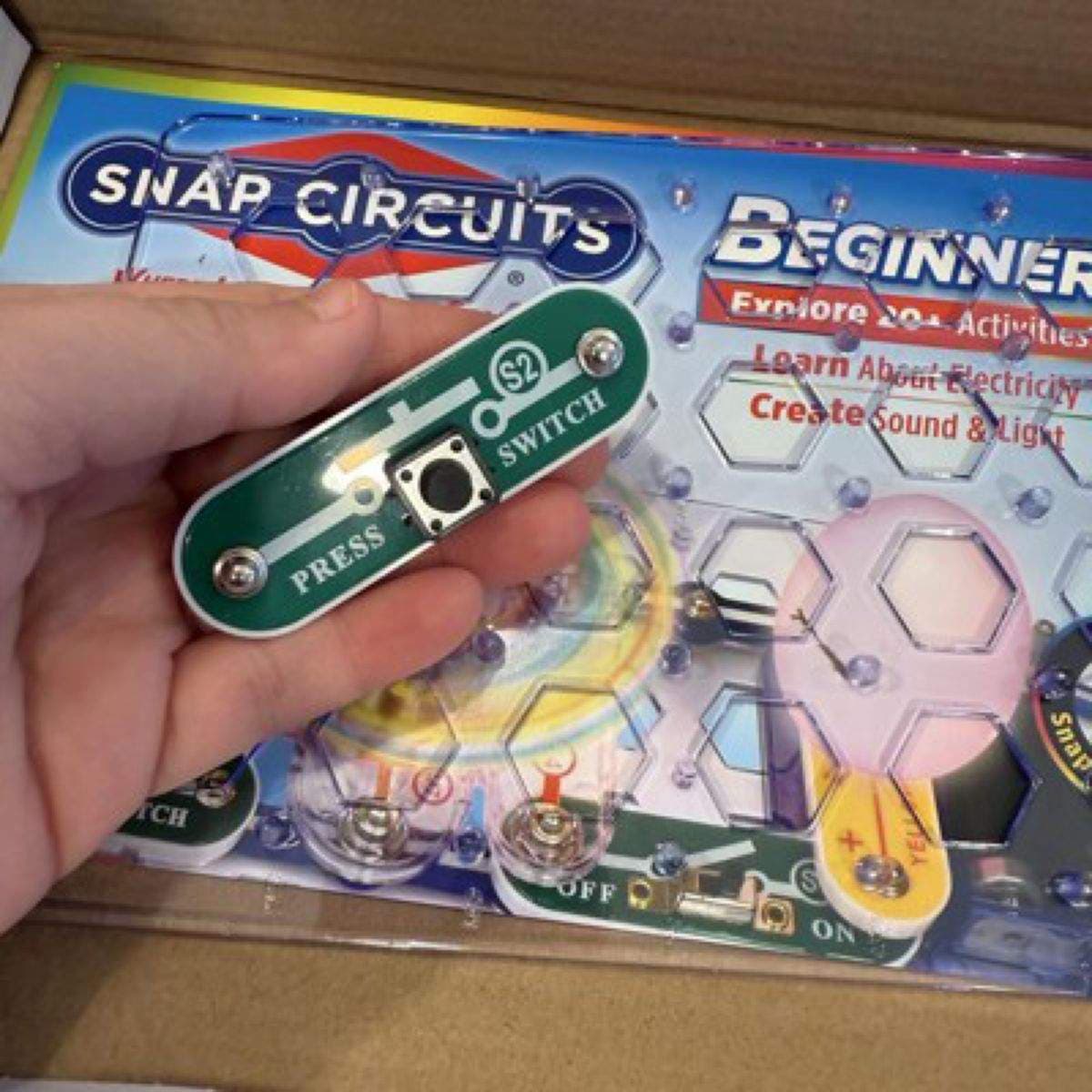 Hand holding a Snap Circuits switch component