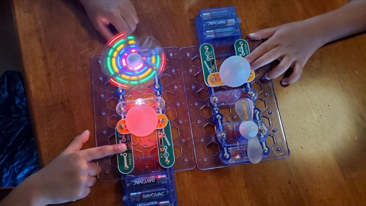 Two Snap Circuits Beginner boards with children's hands building circuits side by side